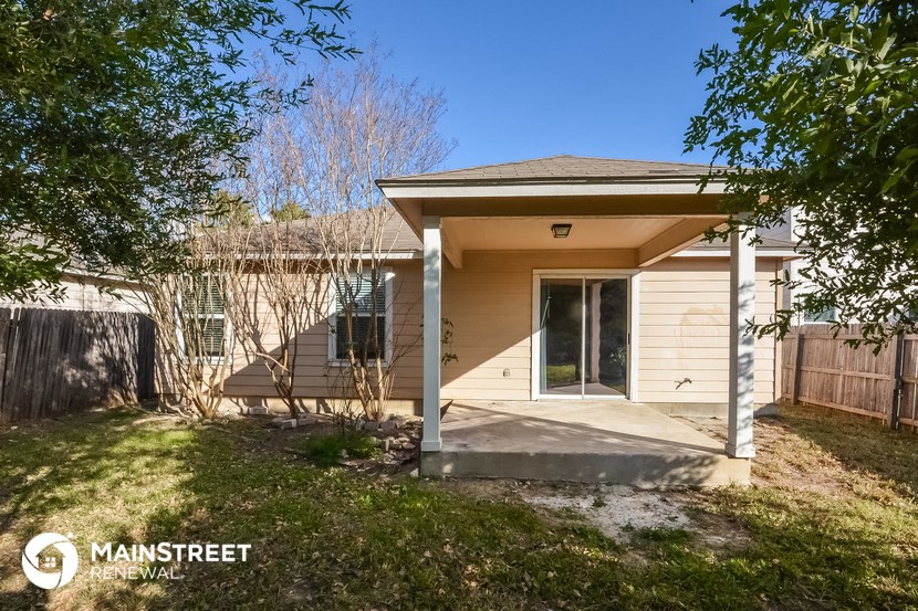 a small tan house with a porch and a yard