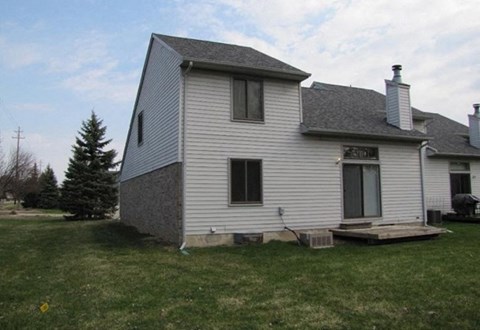 the back of a white house with a gray roof