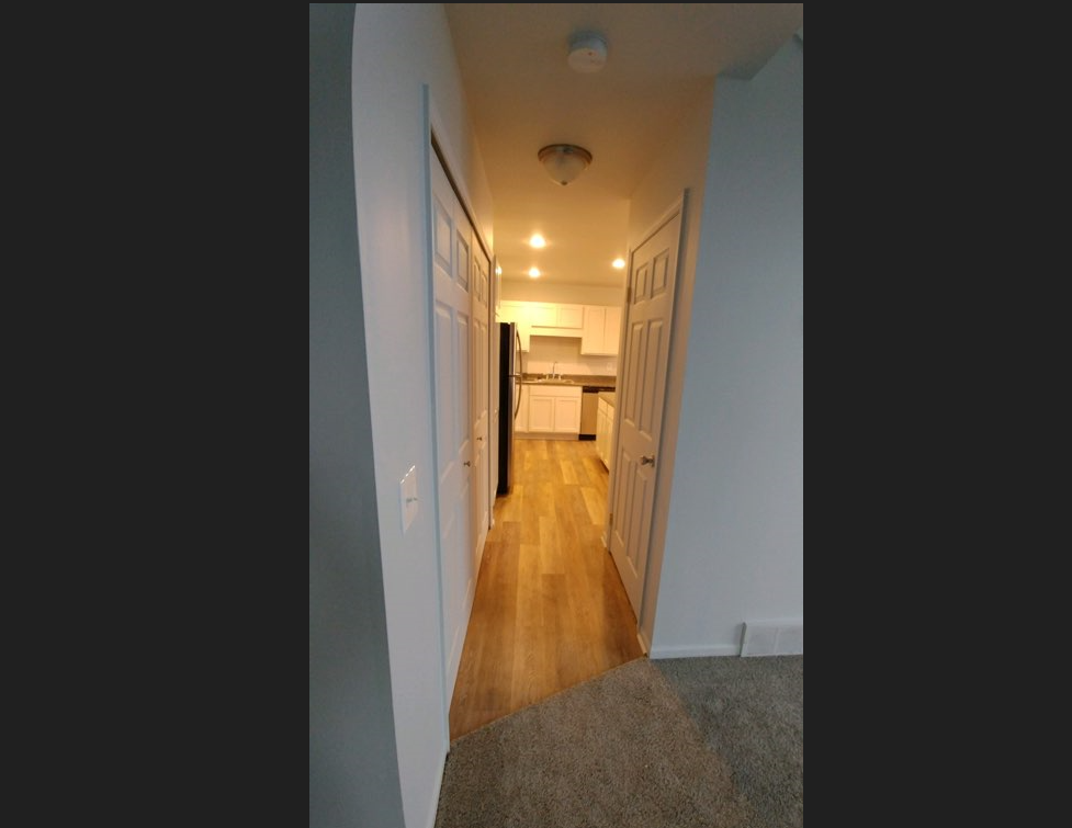 a view of a hallway with a kitchen in the background