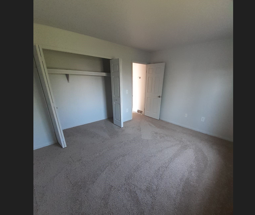 a bedroom with a carpeted floor and a door to a closet