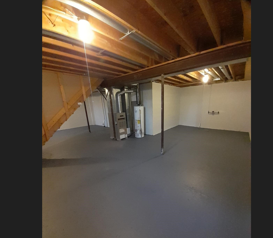 an empty basement with a concrete floor and a staircase