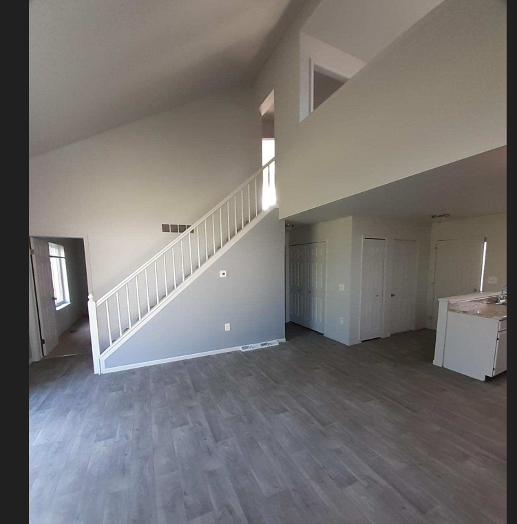 an empty living room with a white staircase