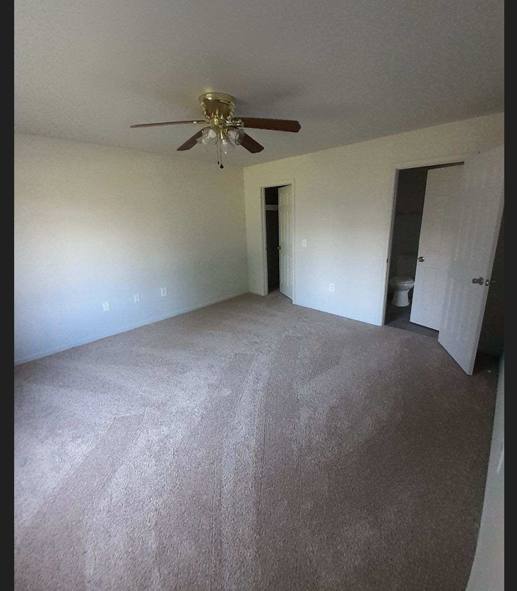 an empty living room with a ceiling fan
