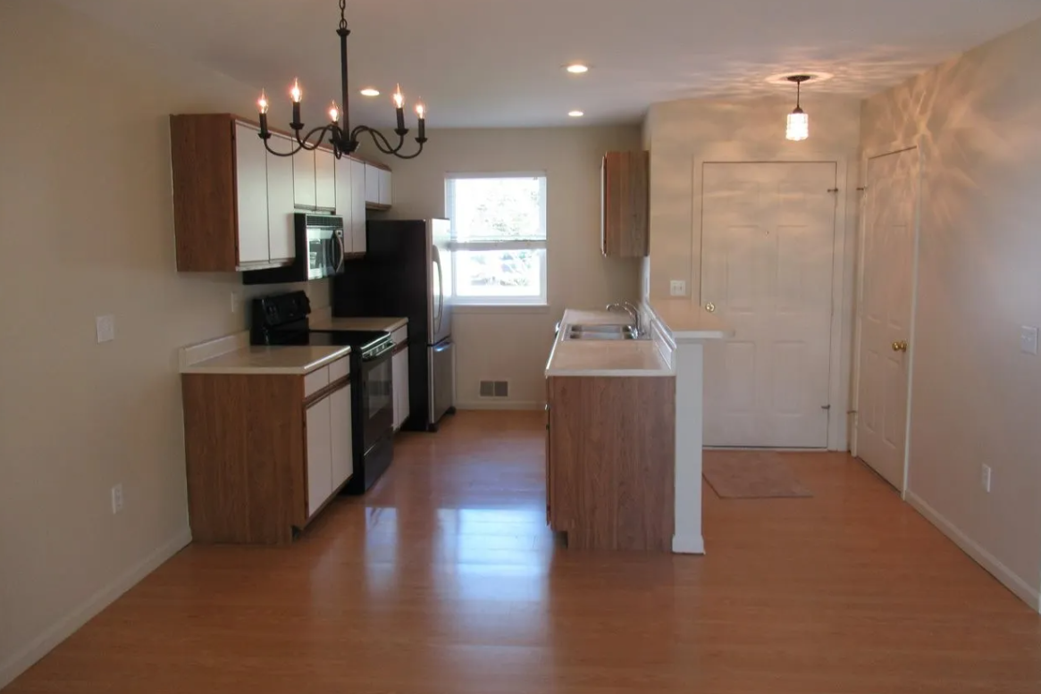 an empty kitchen with wooden cabinets and a window