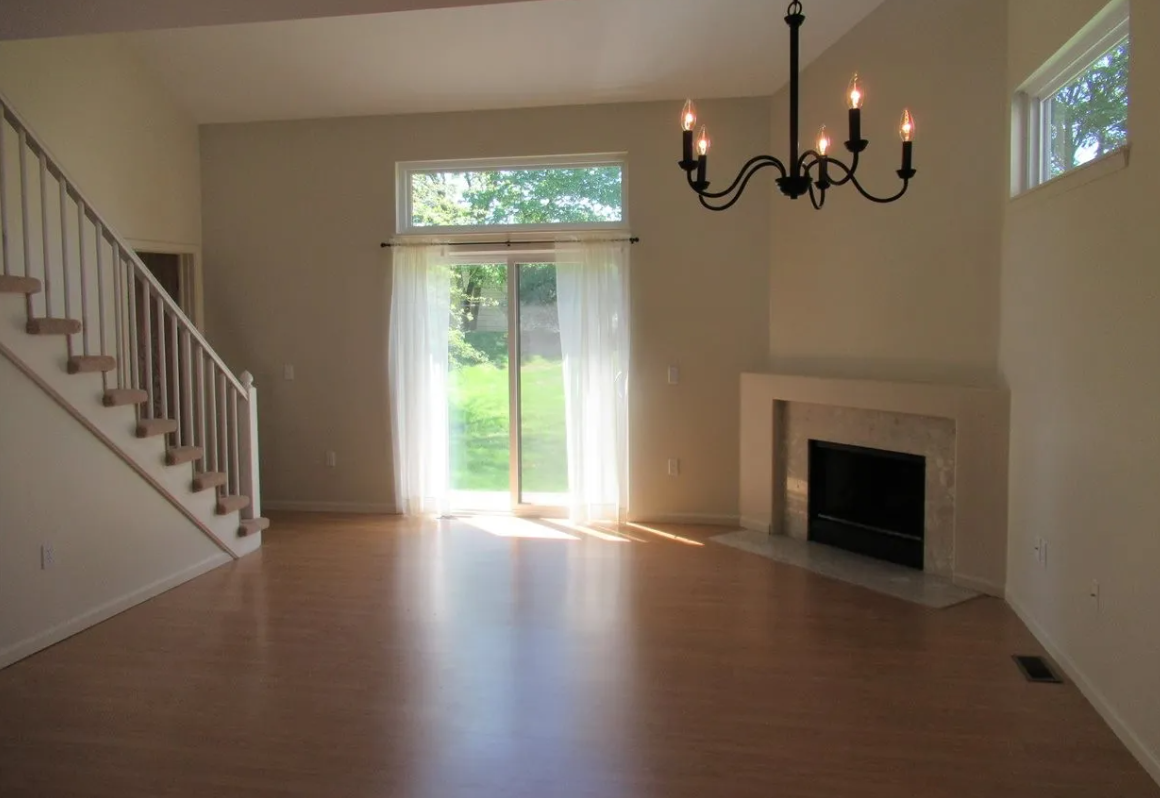 an empty living room with a fireplace and a chandelier