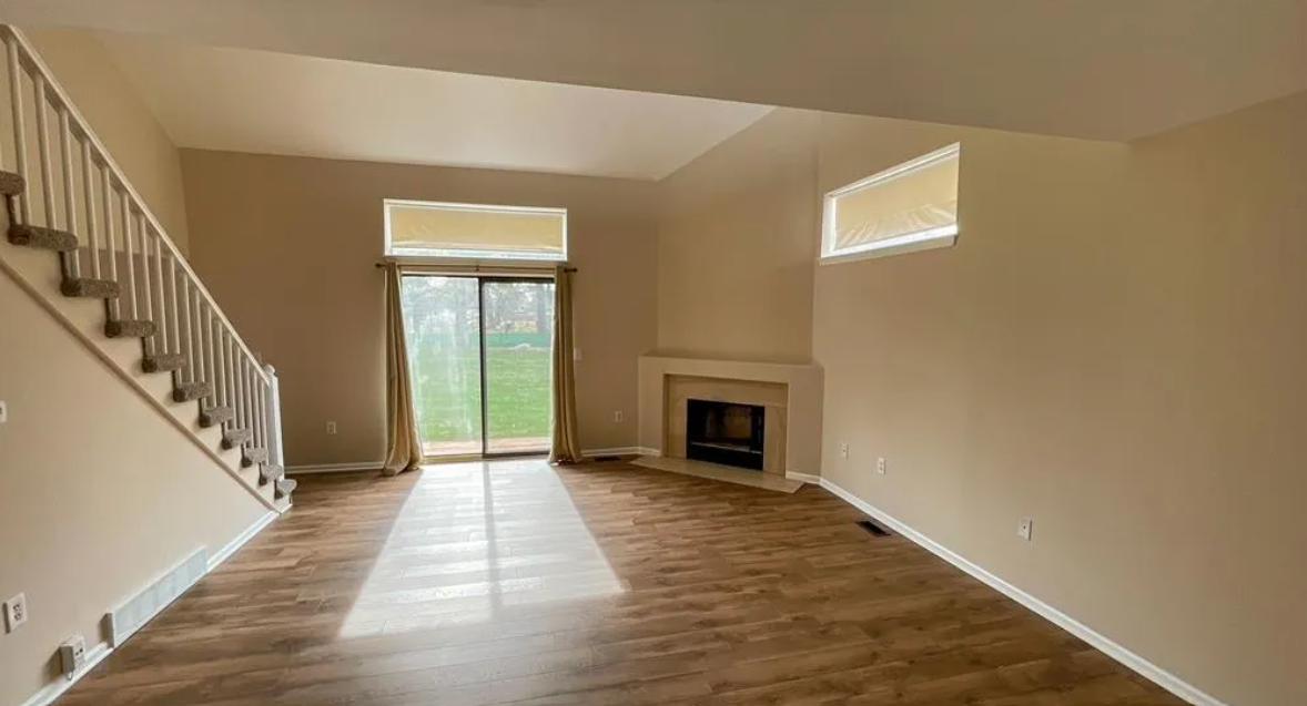 a empty living room with a staircase and a fireplace