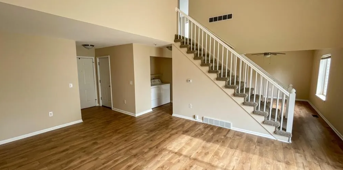 a living room with a staircase and a wooden floor