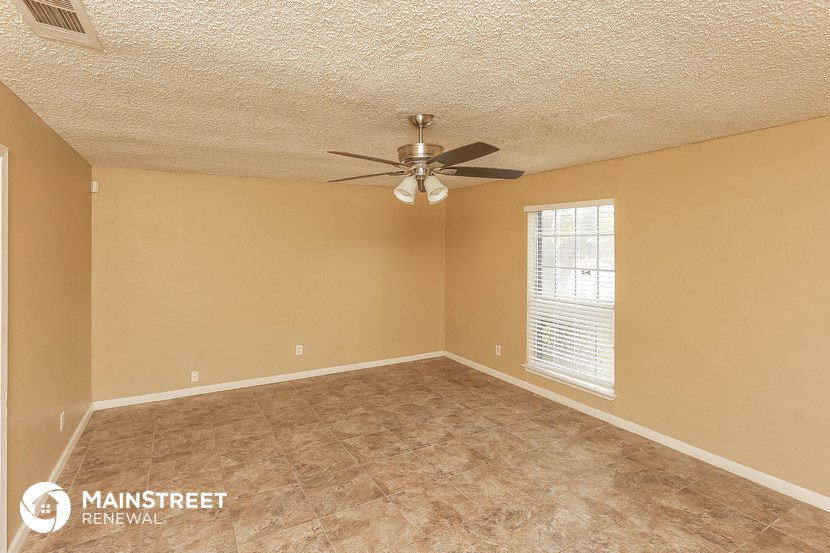 the spacious living room has a ceiling fan and a large window