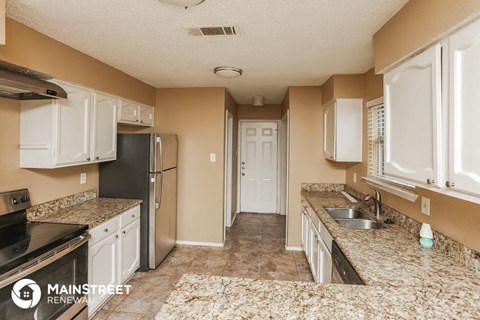 a kitchen with white cabinets and granite counter tops and a stainless steel refrigerator