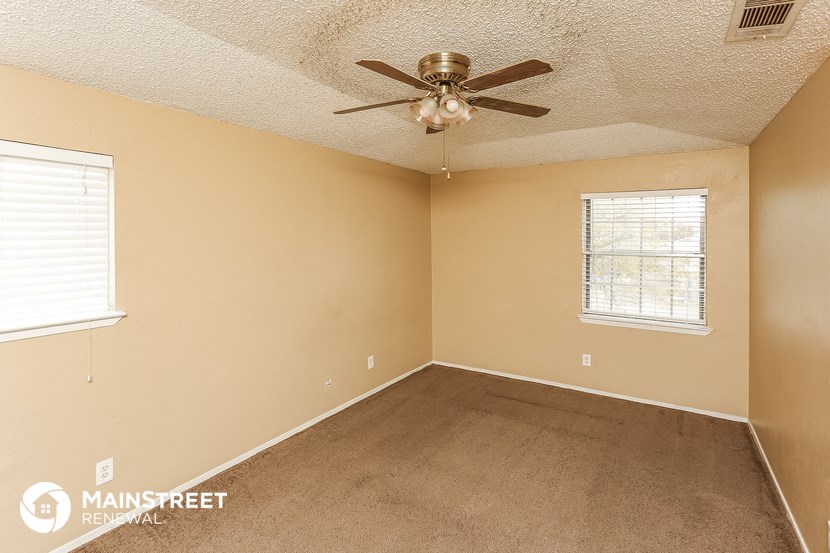 the bedroom of this home has a ceiling fan and a carpet