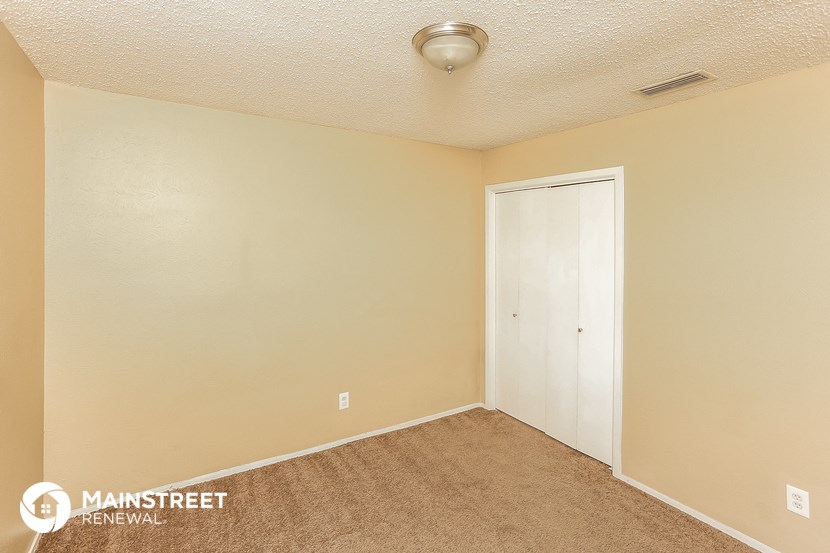 a bedroom with a carpeted floor and a door to a closet