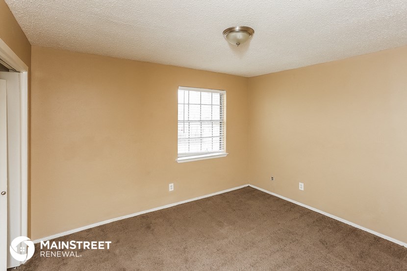 the spacious living room with carpeting and a window
