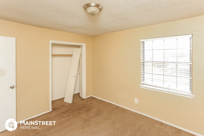 a bedroom with a door to a closet and a window