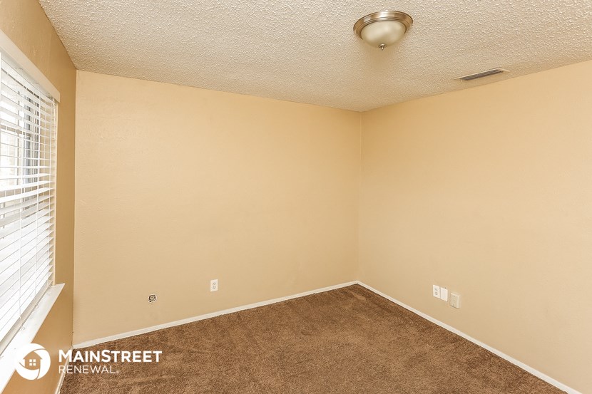 the living room of an empty home with carpet and a window