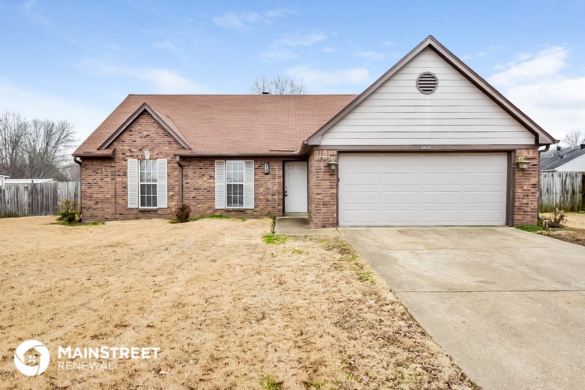 a brick house with a white garage door and a dirt driveway