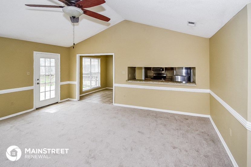 an empty living room with a ceiling fan