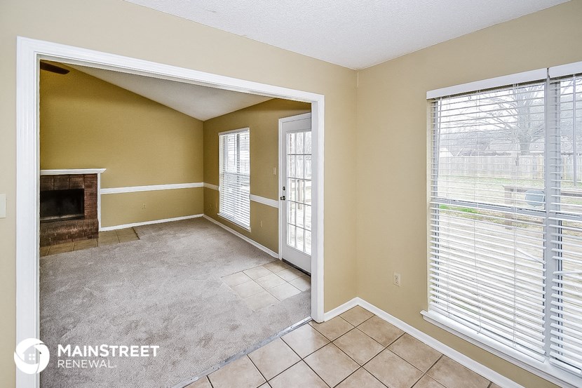 an empty living room with a fireplace and a tiled floor