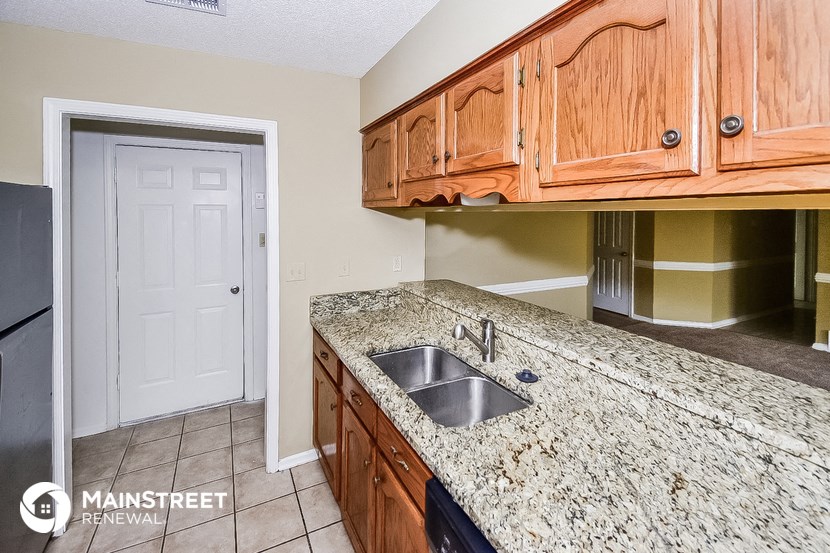 a kitchen with granite counter tops and wooden cabinets and a white door