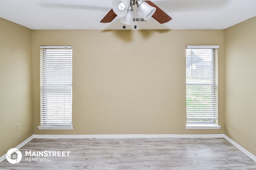 a living room with a ceiling fan and two windows