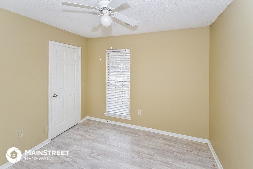 a bedroom with a ceiling fan and a white door