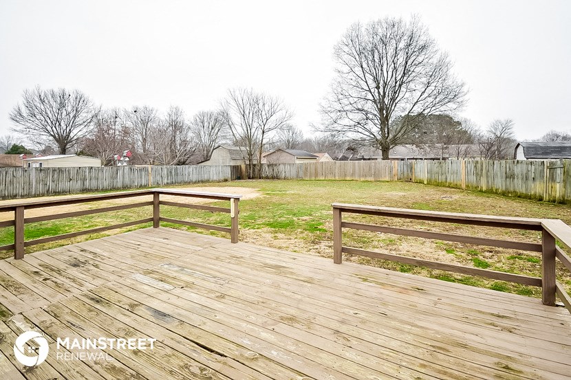 a backyard with a wooden deck and a fence