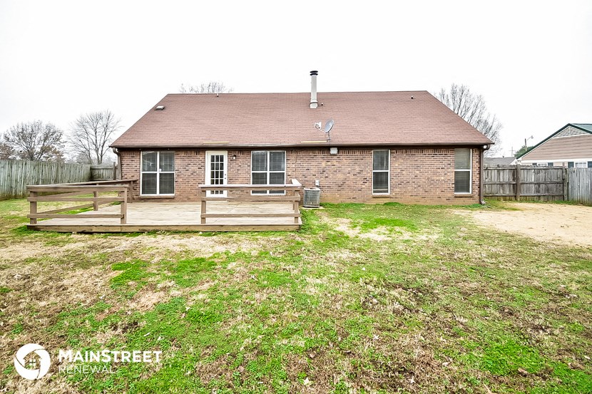 the backyard of a brick house with a wooden deck