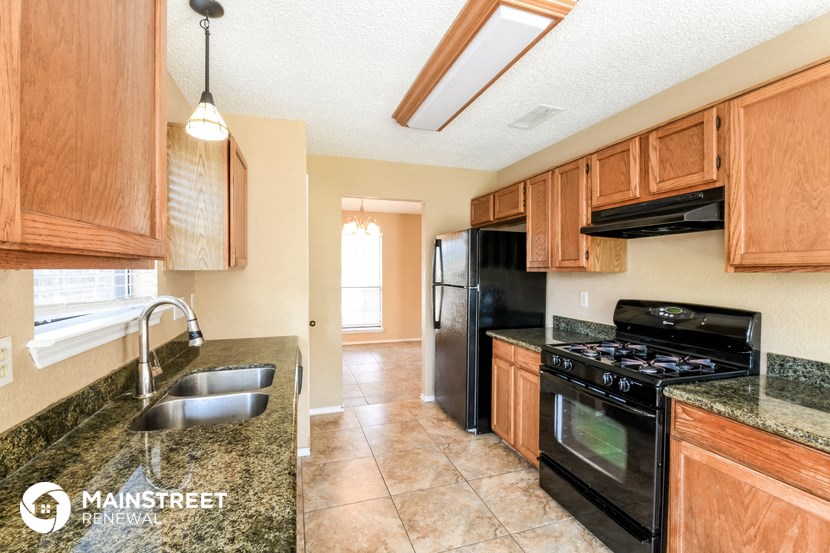 a kitchen with black appliances and granite counter tops and wooden cabinets