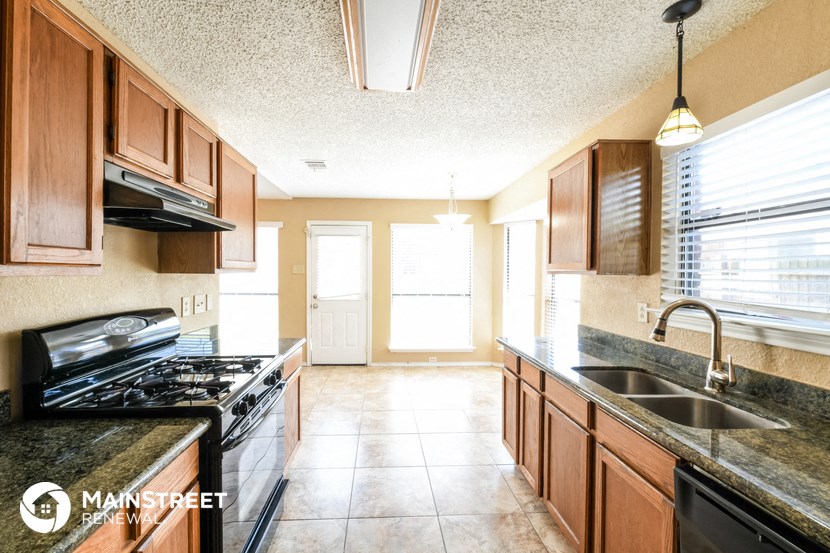 a kitchen with wood cabinets and black counter tops and a sink