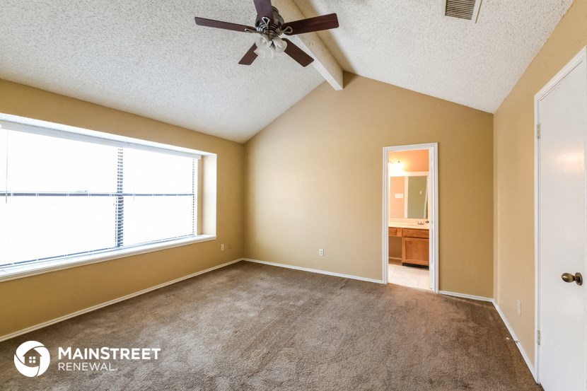 an empty living room with a ceiling fan and a window