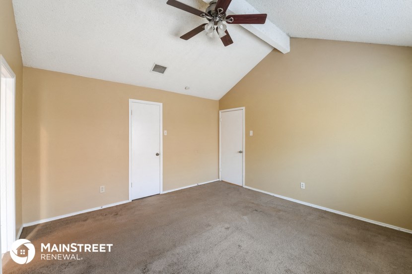 the living room of this home has carpet and a ceiling fan