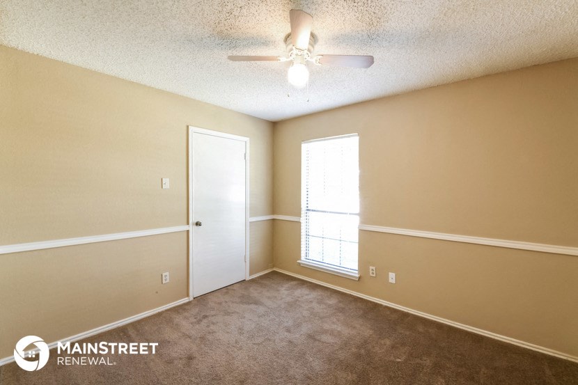 the spacious living room with ceiling fan and window