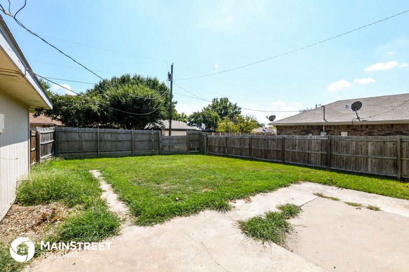 a backyard with a wooden fence and a yard with grass