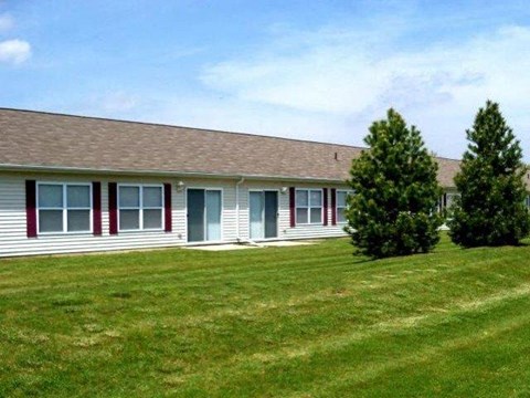 a white house with red doors and a grassy yard