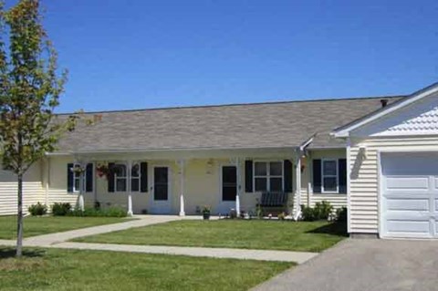 a white house with a gray roof and a lawn