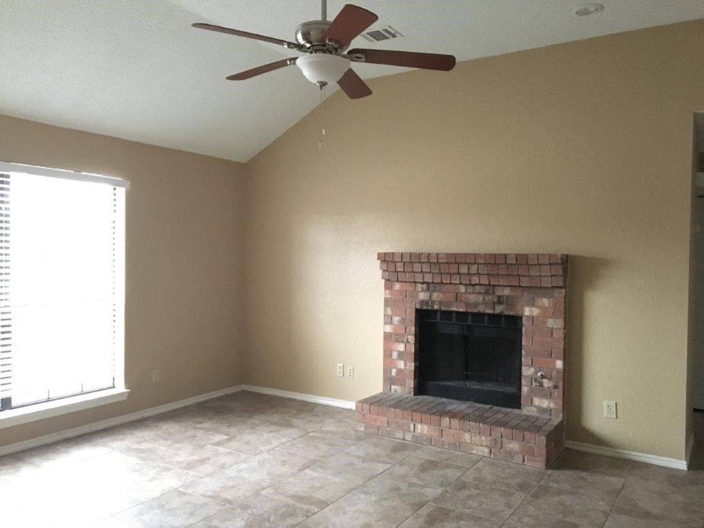 a living room with a brick fireplace and a ceiling fan