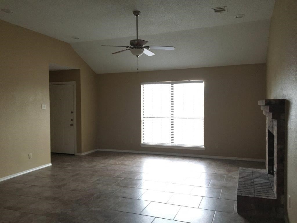 an empty living room with a ceiling fan and a window