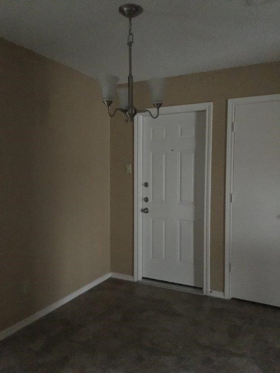 an empty room with a white door and a chandelier