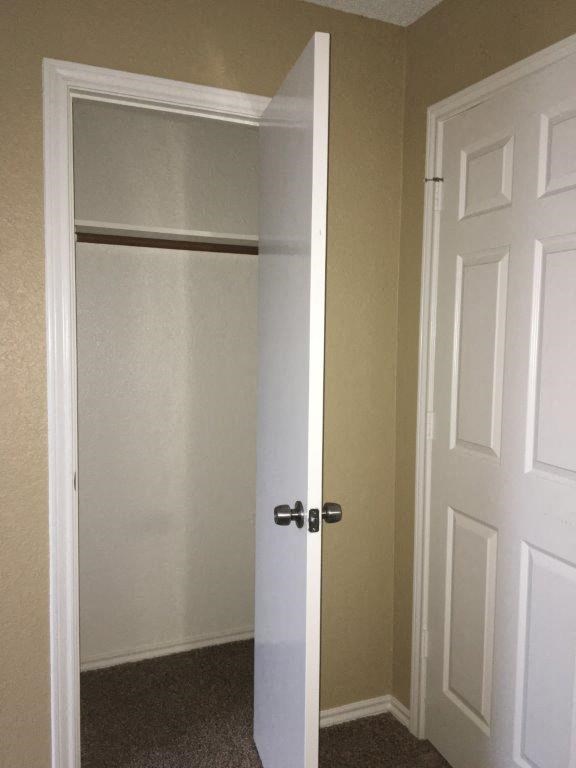 a closet with a white door and an open closet door