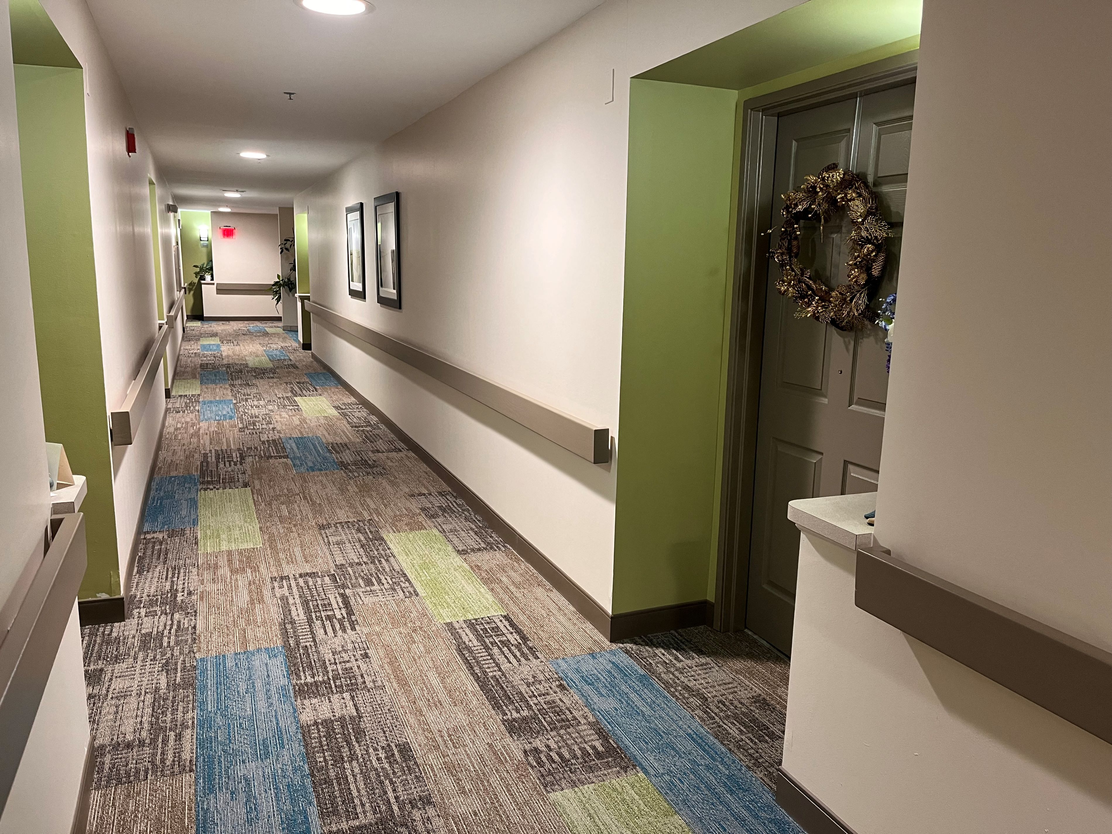 a hallway with green and white walls and a colorful carpet with a door