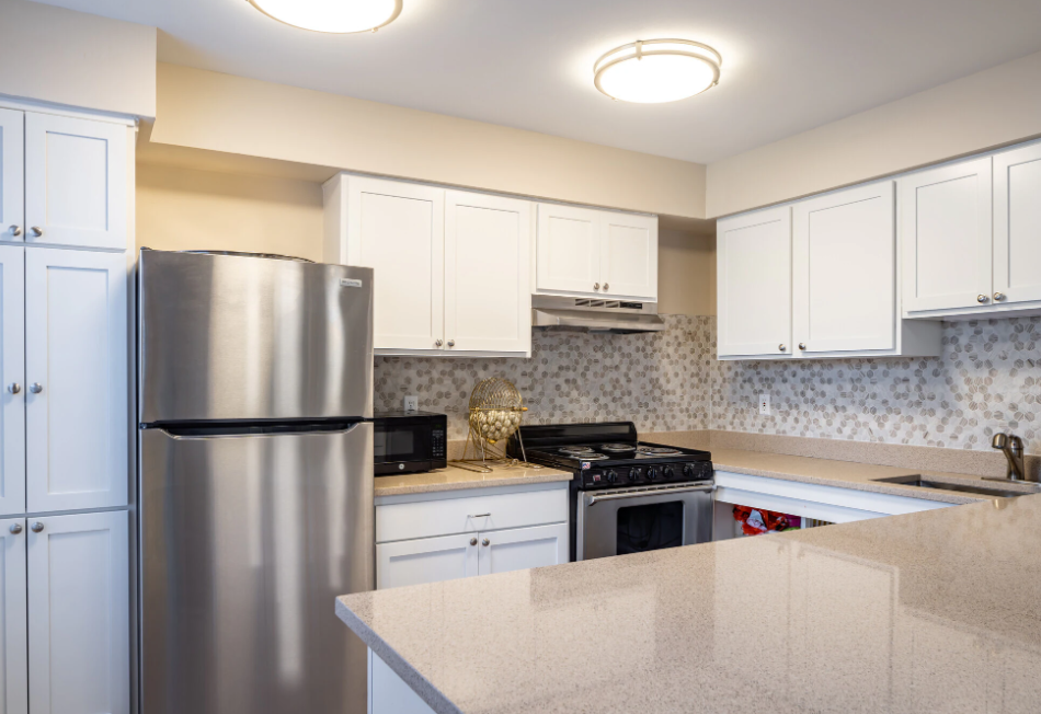a kitchen with white cabinets and a stainless steel refrigerator