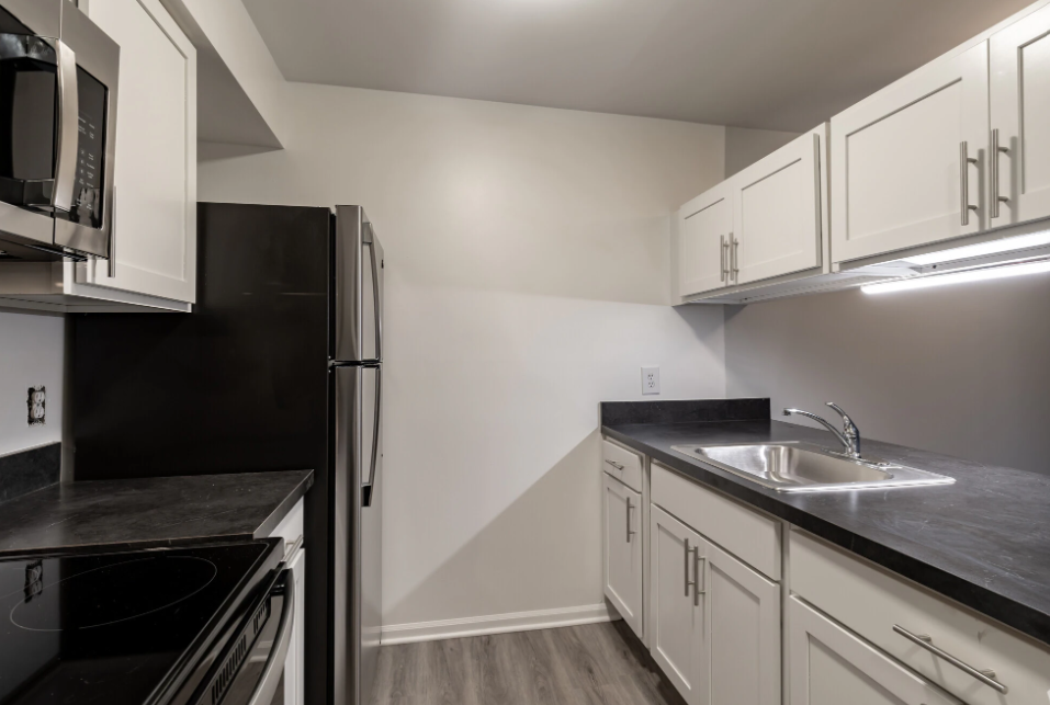 an empty kitchen with black appliances and white cabinets