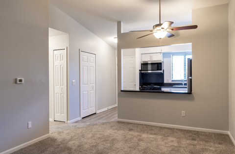 an empty living room with a mirror and a ceiling fan