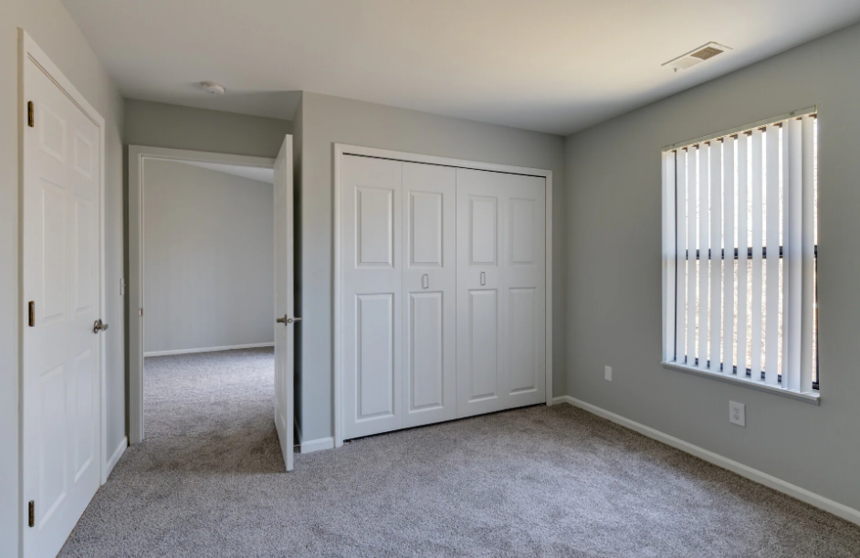 an empty bedroom with white doors and a closet