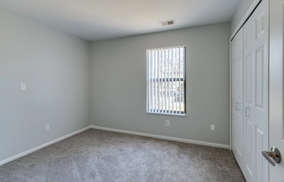 an empty bedroom with a window and a closet