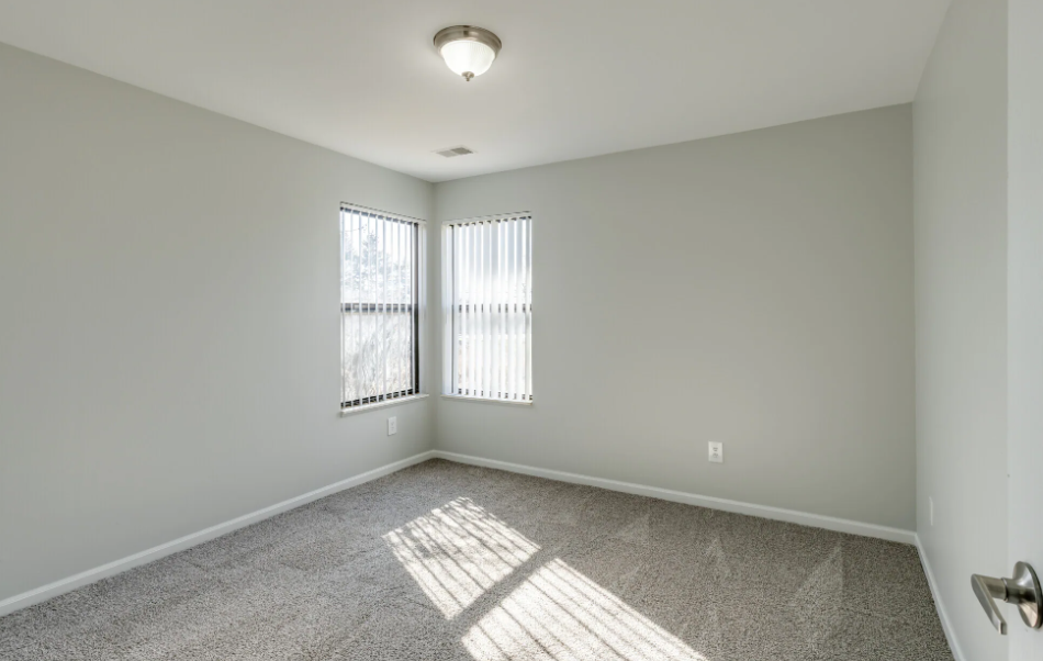 an empty living room with two windows and a ceiling light