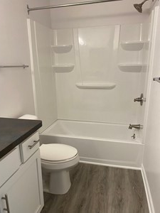 a white bathroom with a toilet and a bath tub
