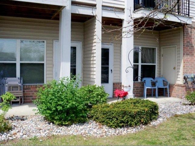 a front porch of a house with chairs and bushes