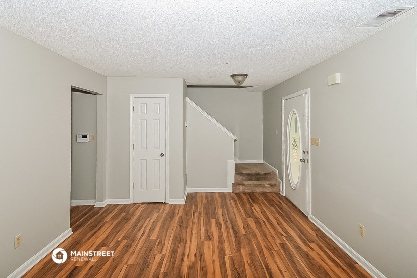 a living room with a hard wood floor and a white door