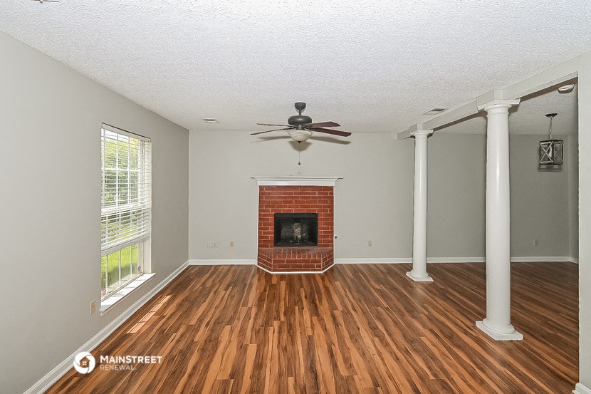 an empty living room with a fireplace and a ceiling fan