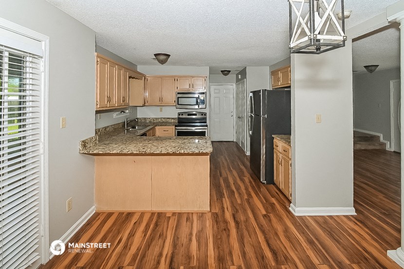 a kitchen with wood flooring and stainless steel appliances